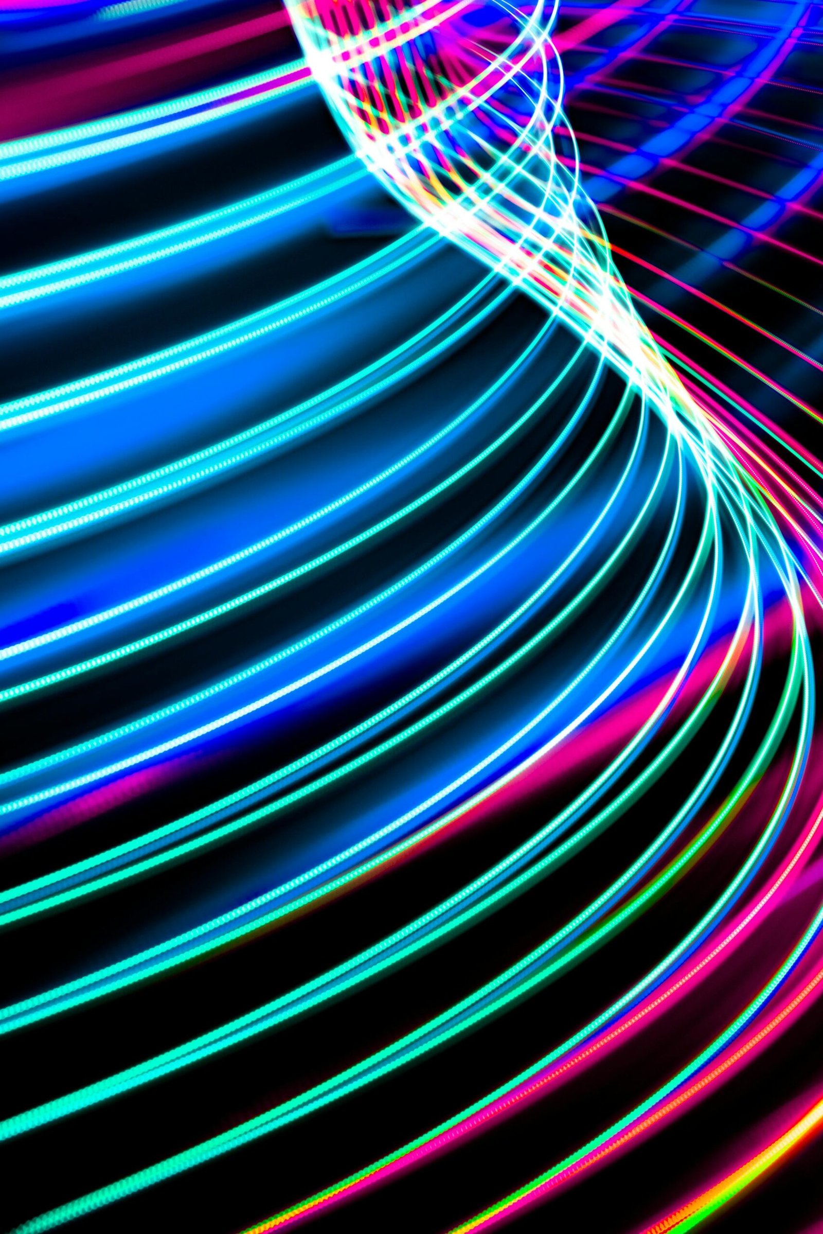 Dynamic abstract image of neon light trails creating colorful curved patterns over a dark backdrop.